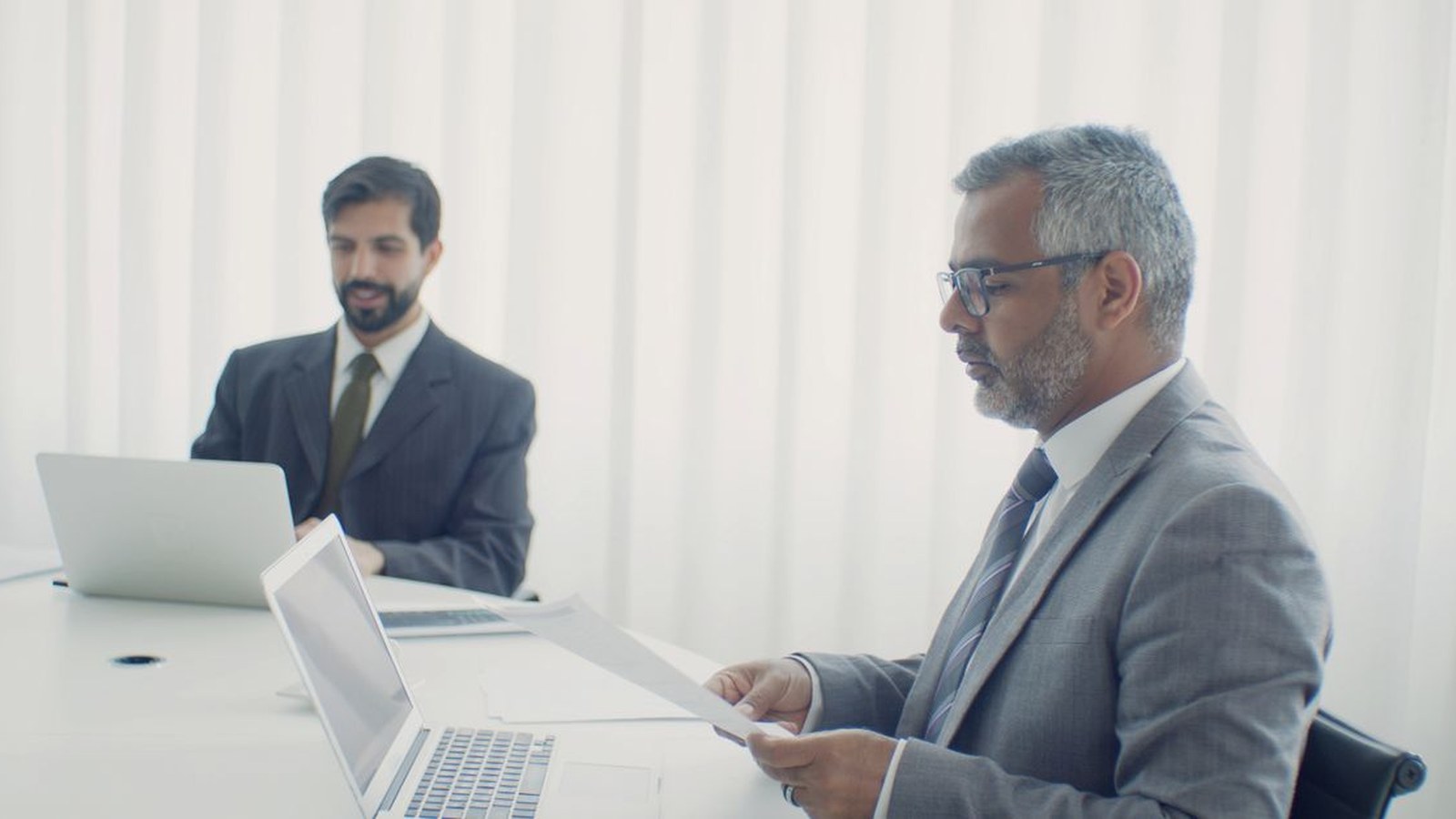 رجلان يراجعان مستندات وحاسوبًا قبل إتمام عملية دفع
