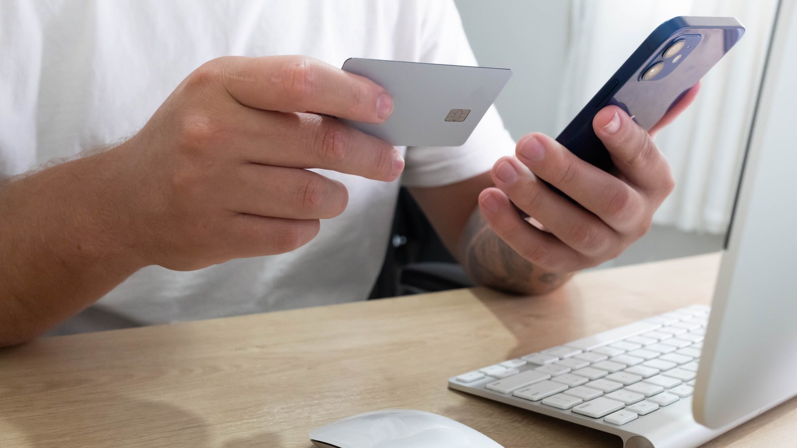 يد رجل تستخدم هاتفًا وبطاقة لإتمام دفع إلكتروني