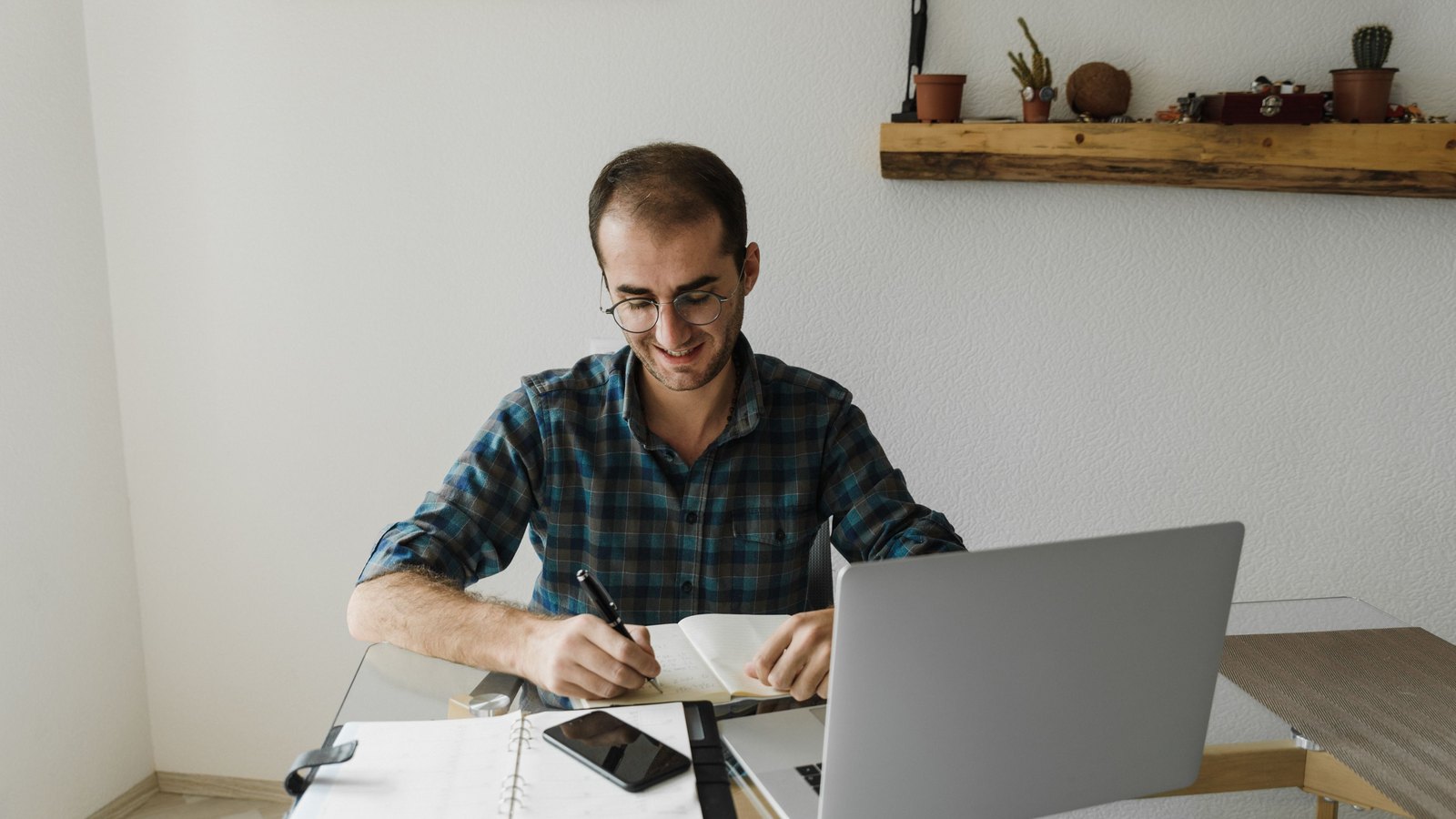 طالب يراجع صيغ Excel ويكتب ملاحظات بجوار الحاسوب